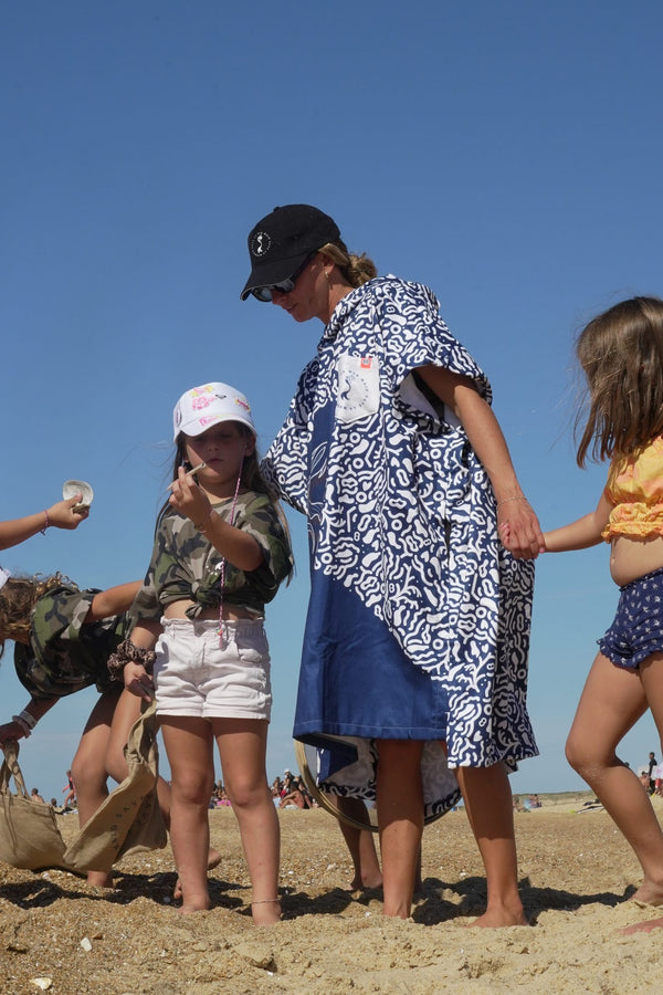 Maud Le Car en poncho Save La Mermaid avec des enfants dans la dune