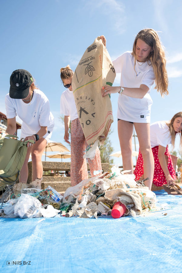 Jeunes benevoles portant un sac de dechets collectes